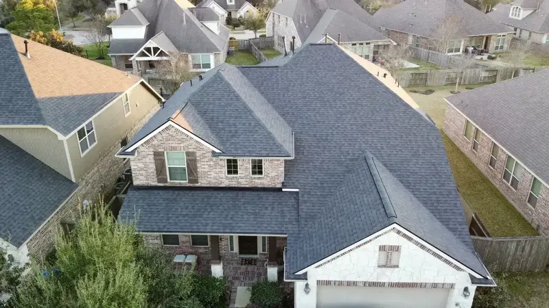 Two-story brick and stone home with a new charcoal shingle roof in a Northwest Houston neighborhood